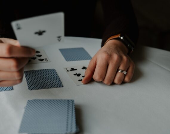 person holding playing cards on white table